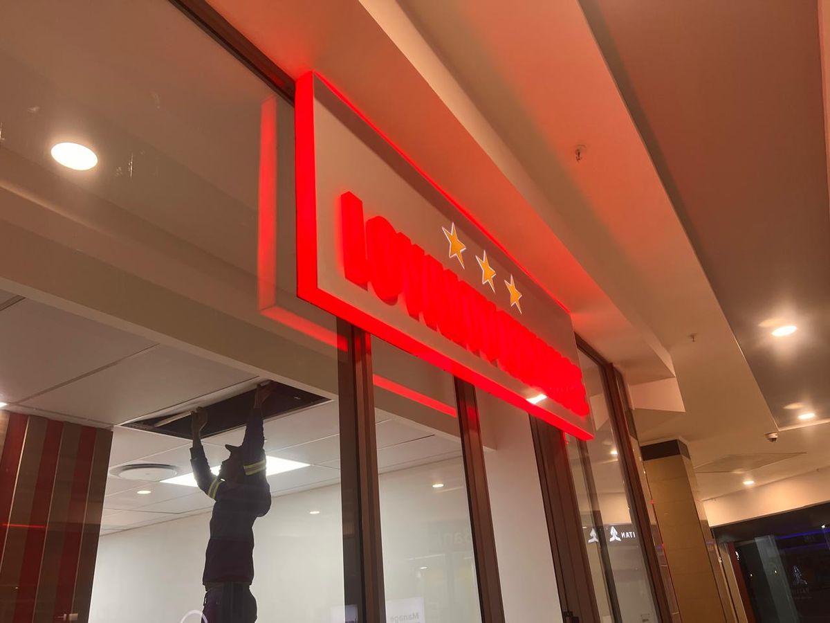 Red glowing illuminated shopfront sign being installed