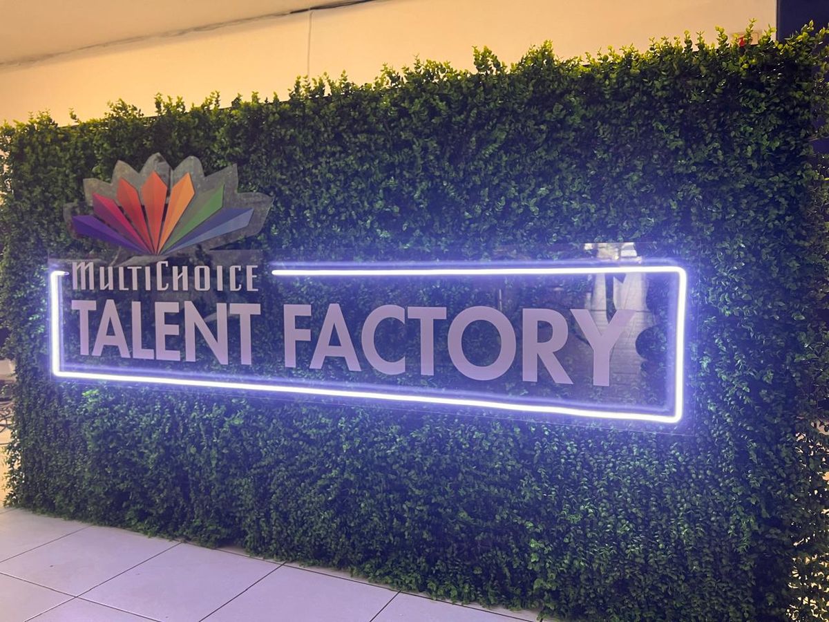 MultiChoice Talent Factory illuminated sign on an artificial green wall at night