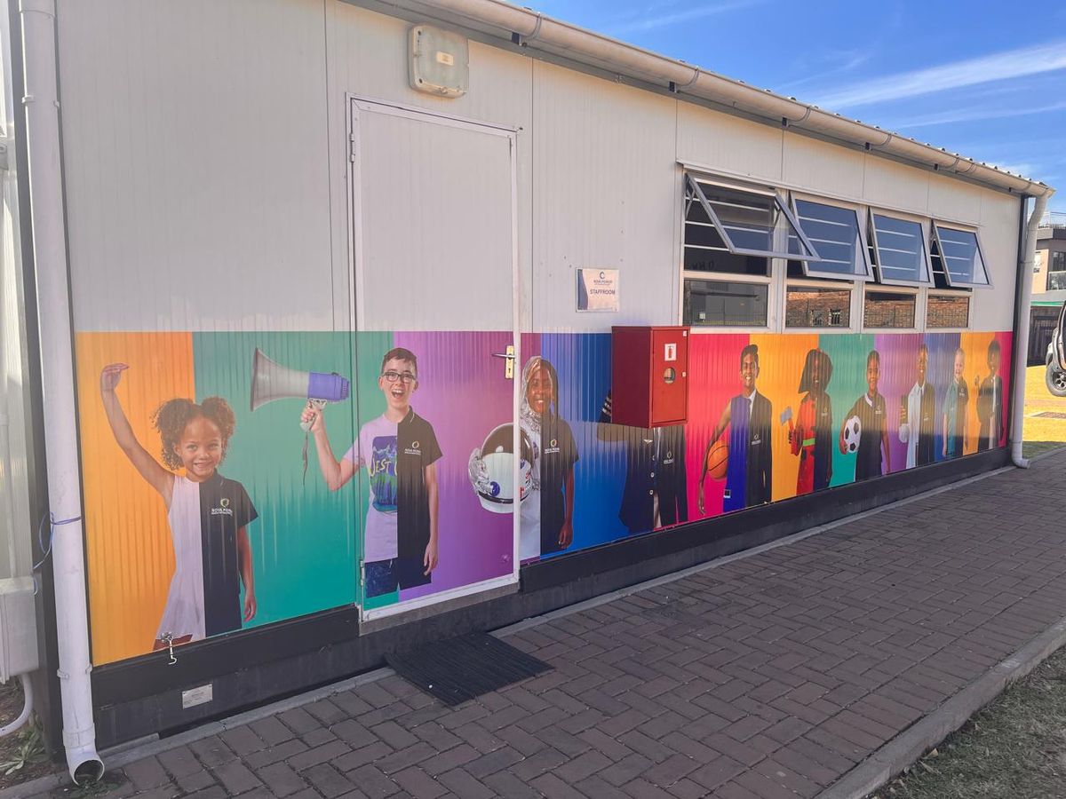 Colourful printed mural of students on a school building wall