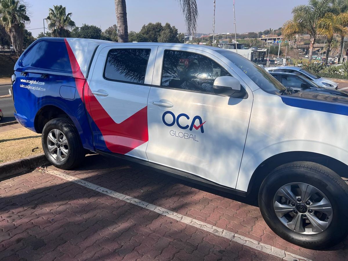 White bakkie with red and navy OCA Global partial wrap