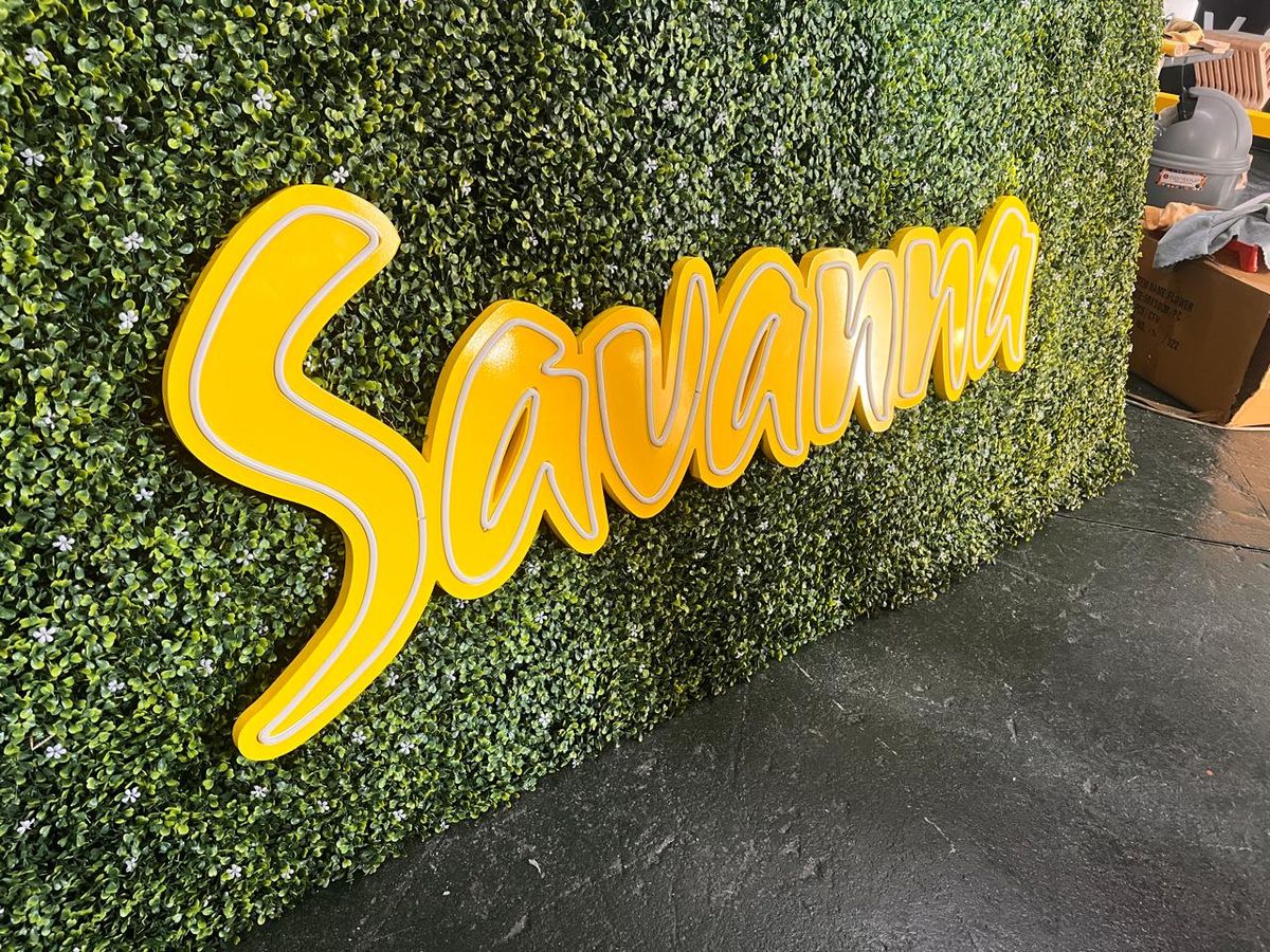 Savanna yellow script sign on an artificial green wall in daylight